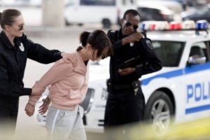 A driver is handcuffed in front of her car