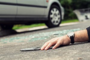 A hand of a car accident victim lying on the road