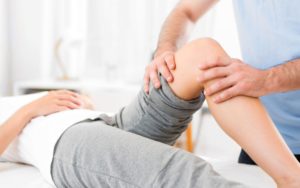 A physical therapist helps a patient with an injured knee