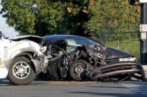 A black car and a white car sit at an intersection after an accident.