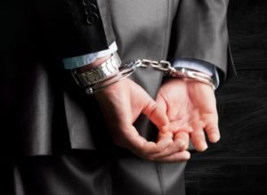 A man in a business suit in handcuffs.