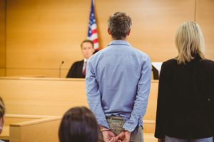 A man in handcuffs stands before a judge