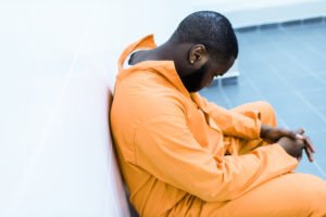 A prisoner looking sad in jail.