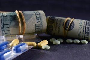 Rolls of cash sit next to pills