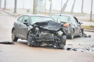 Two cars damaged cars on the road after a head-on collision.