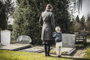 A woman and her child mourning at a gravesite.
