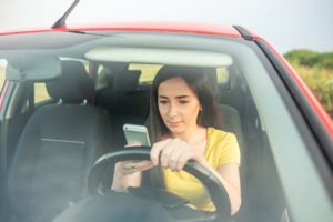 A woman reads her smartphone while driving