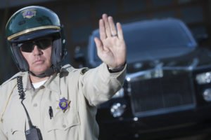 A police officer with his hand raised to signal a stop.
