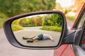 A rearview mirror view of an injured man lying on the road.