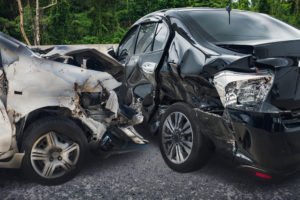 A t-bone crash between white and black cars.