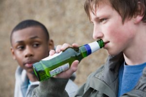 A teen drinking from a beer bottle.