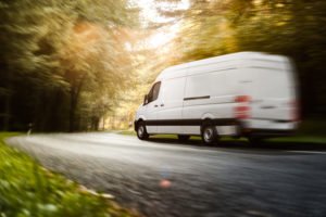 A white van driving fast on a road.