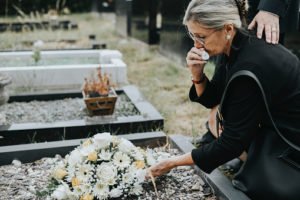 A woman laying flowers on a grave.