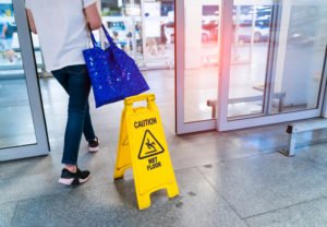 A woman walking past a wet floor sign.