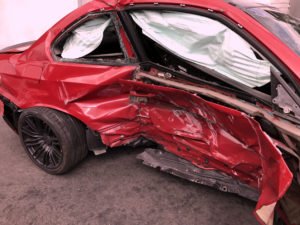 Red car with damage to passenger-side.