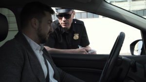 A driver in a suit, talking to a police officer.