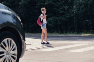 girl about to cross a busy road on her phone