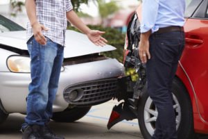 Two drivers talking at an accident scene after their cars collided.