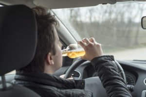 young guy drinking behind the wheel