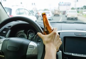 person driving while holding a beer bottle