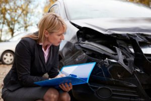 insurance adjuster inspects damaged vehicle